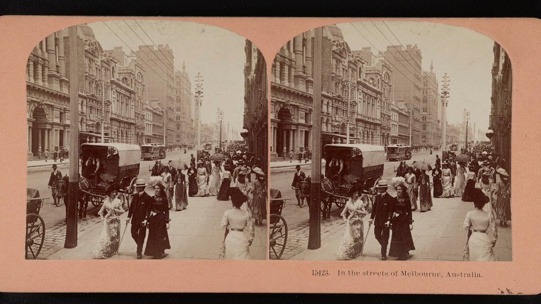 Stereophotograph of a street in sepia colours: people walking along the street in old-fashioned clothes, horsedriven cab on the street and a lane of buildings on the left.