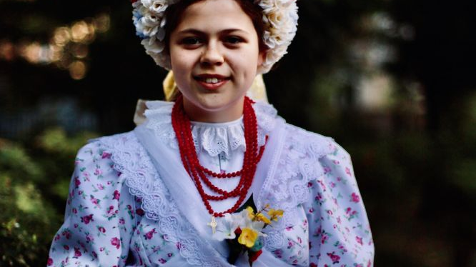 A young woman in traditional costume and with decorative headgear on her head.