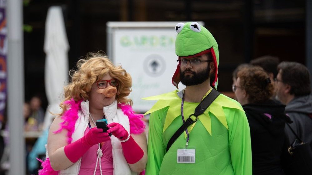 A woman and a man in disguise - one of them as Kermit the frog and another as Miss Piggy