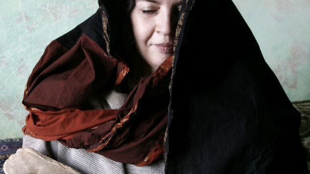 Artystka ma na sobie ciemny, zdobiony woal, który zakrywa jej włosy i większość twarzy. Pozuje z tajemniczym wyrazem twarzy, trzyma w rękach starodawny instrument.