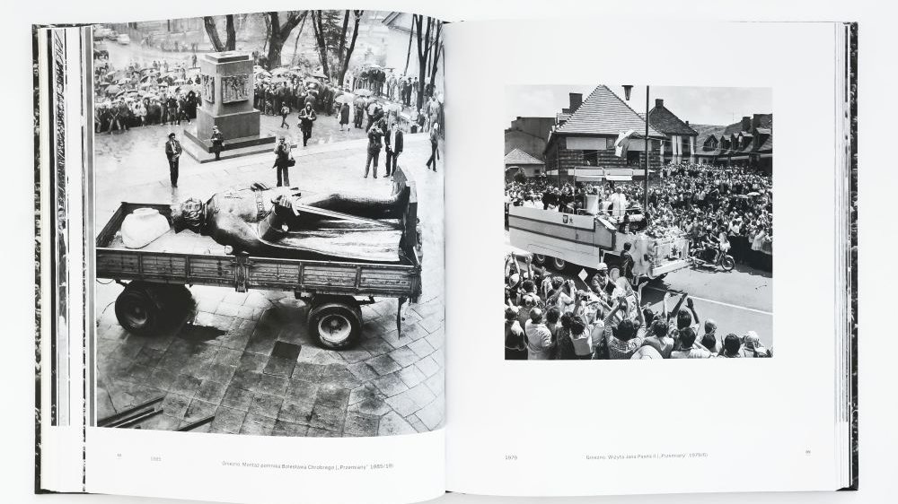 Rozkładówka albumu fotograficznego. Po lewej pomnik jadący na przyczepie ciągnika, po prawej wiwatujące przy drodze tłumy.