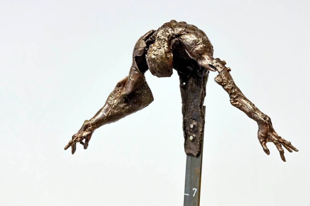 Rzeźba przypominająca odlanego z mosiądzu, mocno pochylonego człowieka z rozcapierzonymi rękami. - grafika artykułu