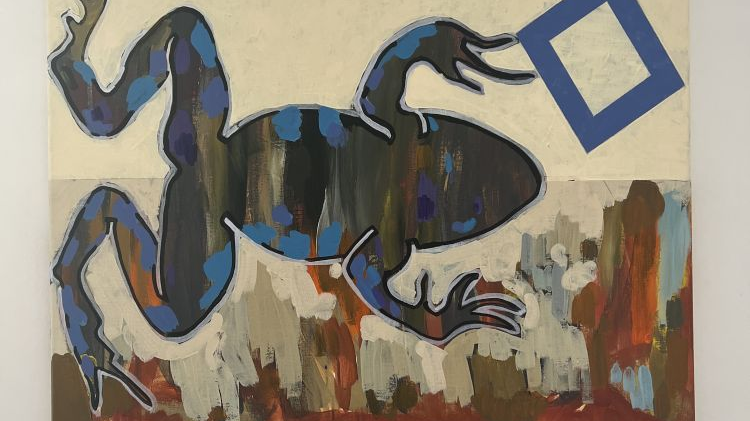Na obrazie szara żaba pokryta gdzieniegdzie niebieskimi ciapkami trzyma granatowy prostokąt. Na dole obrazy kolorowe smugi wykonane farbami.