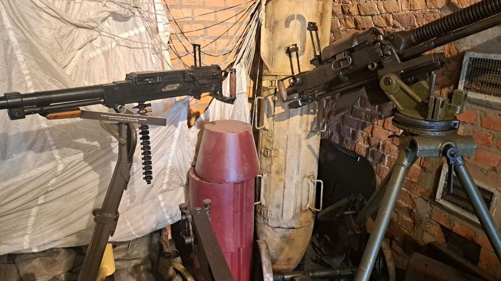 Ekspozycja muzealna z bronią maszynową po prawej i lewej stronie.